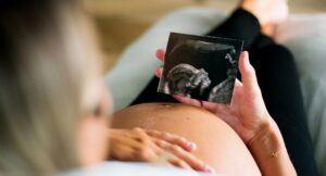 pregnant woman looking at an ultrasound image of her baby